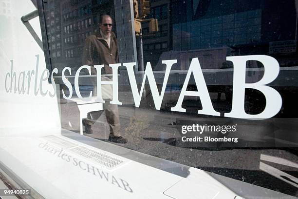 Pedestrian is reflected in the window of a Charles Schwab branch in New York, U.S., on Tuesday, Feb. 24, 2009. Charles Schwab Corp. And other 401...