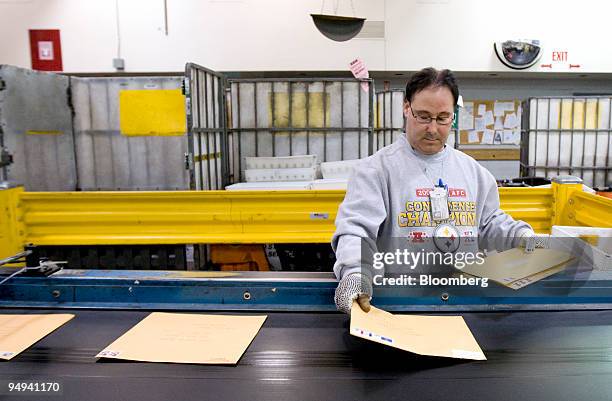 Postal worker lays down envelopes to be processed at the U.S. Postal Service Mid-Island Processing and Distribution Center in Melville, New York,...