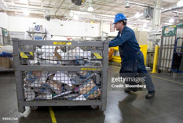 Postal worker pushes a cart filled with magazines and advertisements to be sorted at the U.S. Postal Service Mid-Island Processing and Distribution...