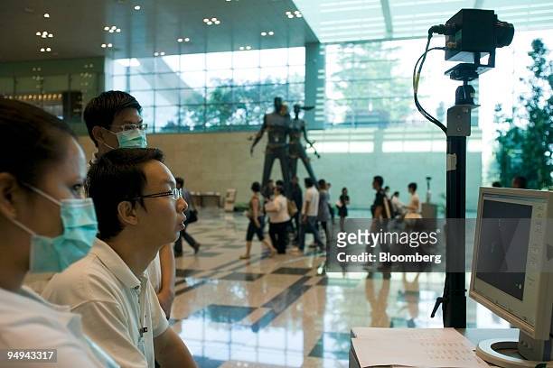 Health workers monitor a thermal scanner as passengers arrive at Changi airport in Singapore, on Monday, April 27, 2009. Singapore has stepped up...