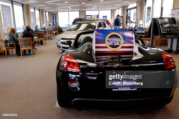 Customers meet with General Motors salesmen as a GM Pontiac Solstice convertible sits on display at the Fred Beans dealership in Doylestown,...
