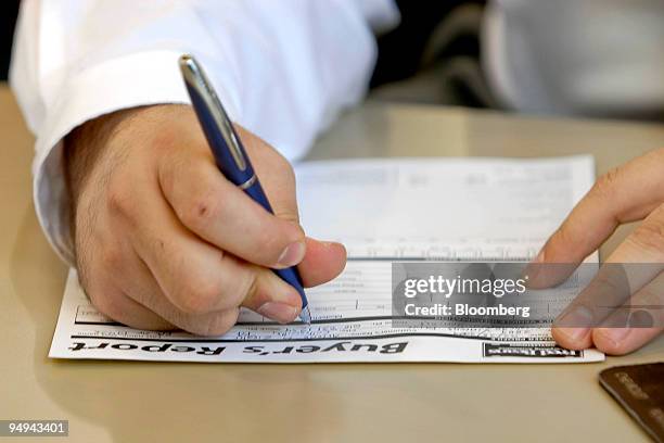 Salesman fills out a buyer's report while working with a customer purchasing a General Motors vehicle at Fred Beans dealership lot in Doylestown,...
