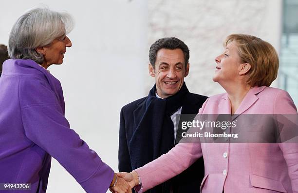 Angela Merkel, right, Germany's chancellor, welcomes Christine Lagarde, left, France's finance minister, watched by Nicolas Sarkozy, France's...