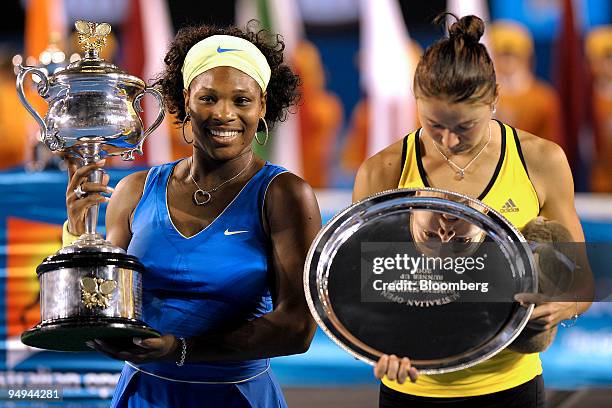 Serena Williams of the U.S., left, holds up the championship trophy as Dinara Safina of Russia is reflected in the runner-up plaque following their...