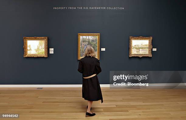 Woman looks over three paintings from the H.O. Havemeyer Collection during a media preview of Sotheby's spring sales of Impressionist, Modem and...