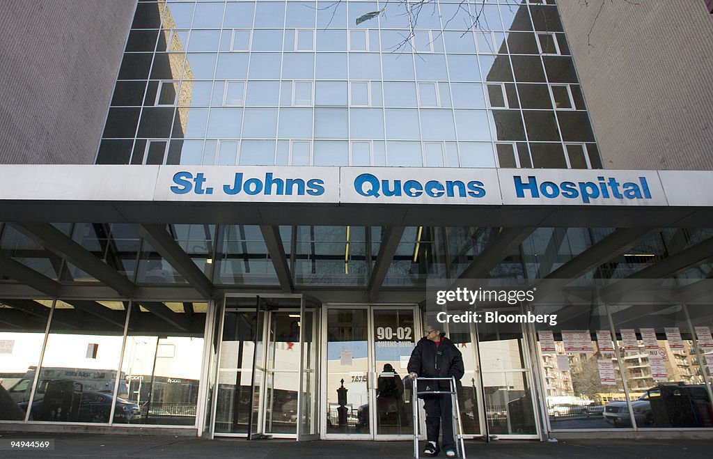 A patient stands in front of St. John's Queens Hospital, a C