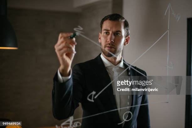 hombre de negocios dibujar un gráfico en pared de vidrio - director financiero fotografías e imágenes de stock