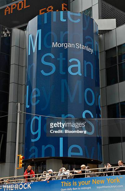 Tourists sit in the open top of a tour bus outside the headquarters building of Morgan Stanley, in New York, U.S., on Wednesday, May 6, 2009. Morgan...