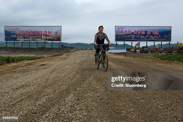 Woman rides a bicycle on a road leading to the new location of the city of Beichuan, which was destroyed in last year's earthquake, near Mianyang,...