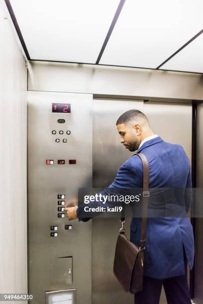 mixed race businessman riding elevator - inside elevator stock pictures, royalty-free photos & images