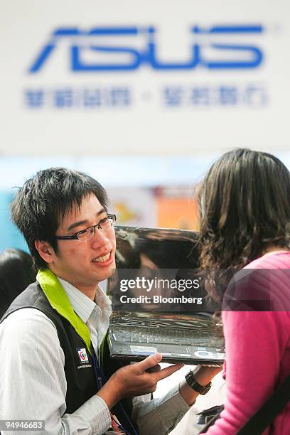 An Asustek Computer Inc. Representative, left, displays a laptop at their booth at an expo in Taipei, Taiwan, on Thursday, Feb. 12, 2009. Asustek,...