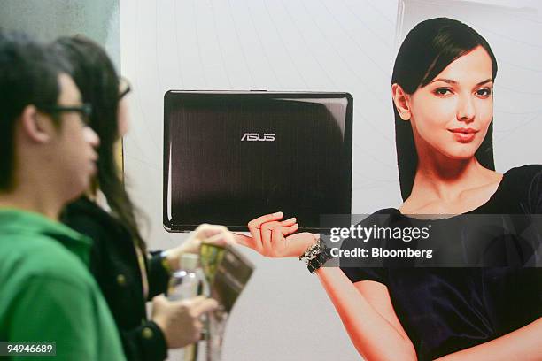 Pedestrians walk past an Asustek Computer Inc. Booth at an expo in Taipei, Taiwan, on Thursday, Feb. 12, 2009. Asustek, the world's largest supplier...