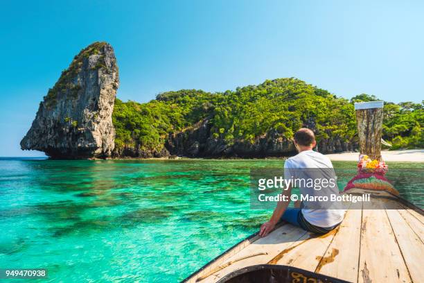 tourist sitting on a longtail boat in phi phi island, thailand - tailandia foto e immagini stock