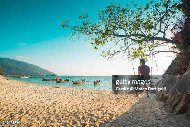 tourist man sitting on swing at the beach, thailand - awesome man foto e immagini stock