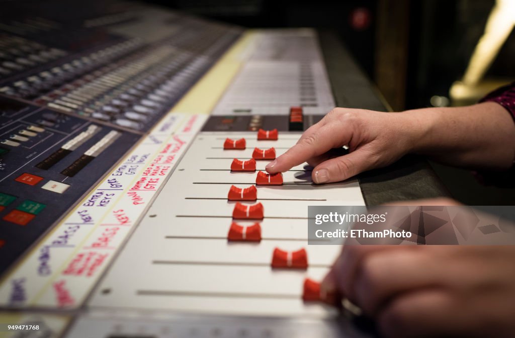 Hands of a sound engineer on audio mixing console at recording studio