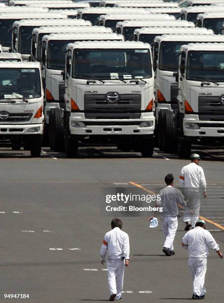 Workers walk near Hino Motors Ltd. Trucks bound for shipment waiting in a lot at a port of Yokohama City, Kanagawa Prefecture, Japan, on Wednesday,...