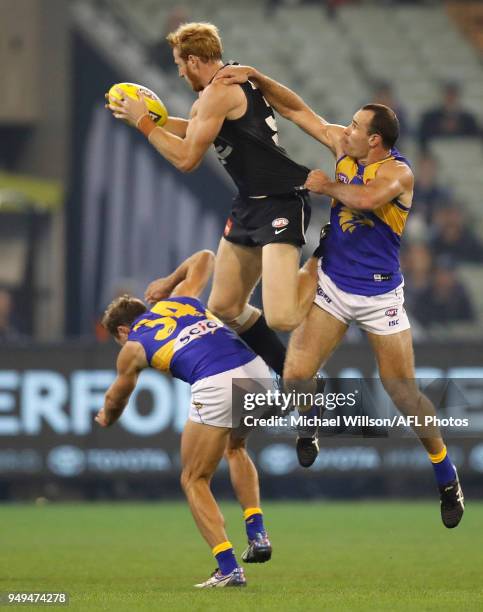 Andrew Phillips of the Blues takes a high mark over Mark Hutchings and Shannon Hurn of the Eagles during the 2018 AFL round five match between the...