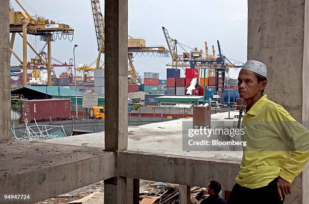Worker watches as his colleagues arrive for Friday prayers at an unfinished mosque in the main container port facility in Jakarta, Indonesia, on...