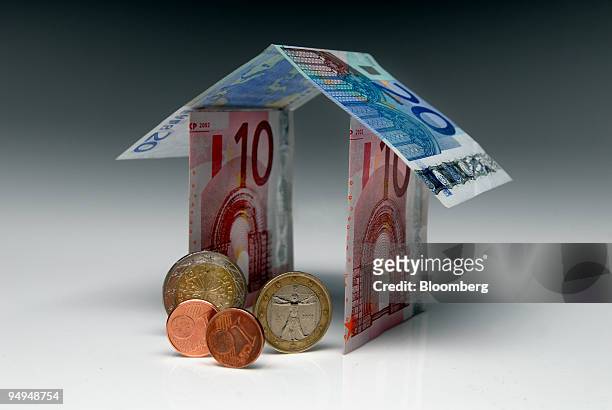 Euro notes and coins form the shape of a house in Paris, France, on Monday, April 27, 2009. German Finance Minister Peer Steinbrueck said that the...