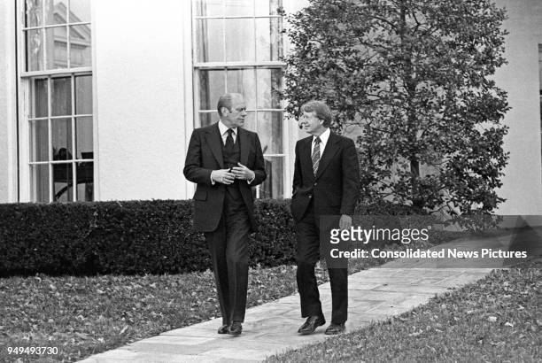 American politicians US President Gerald Ford and US President-Elect Jimmy Carter as they walk together outside the White House, Washington DC,...