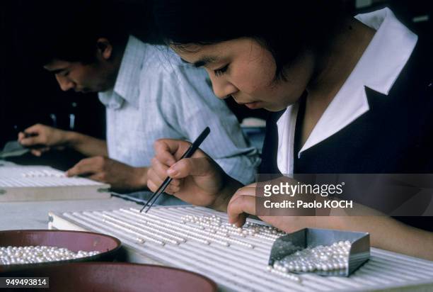 Ouvrière fabriquant des colliers dans une entreprise de culture industrielle de perles à Shima, dans la baie d'Ago, Japon.