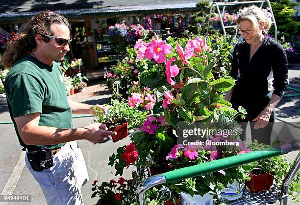 Patrick Gasparro, co-owner of Nature's Cradle garden center, left, assists customer Nancy Armentano as she looks over flowers in Eastchester, New...