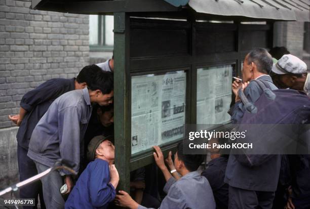 Passants lisant des journaux affichés sur un panneau dans la rue, à Taiyuan, en Chine.