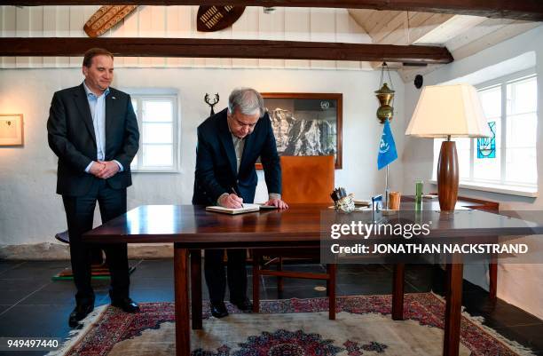 United Nations Secretary-General Antonio Guterres signs the guest book as Sweden's Prime Minister Stefan Lofven look on during the annual informal...