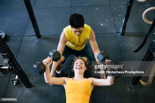 woman doing dumbbell exercises at gym - lying on back photos - fotografias e filmes do acervo