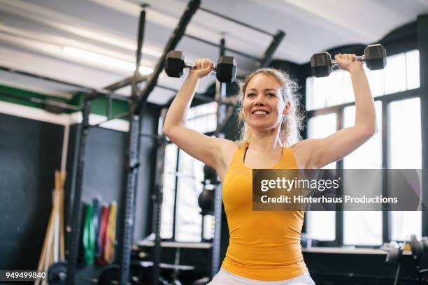 young woman doing dumbbell exercises - levantamento de peso fotografías e imágenes de stock