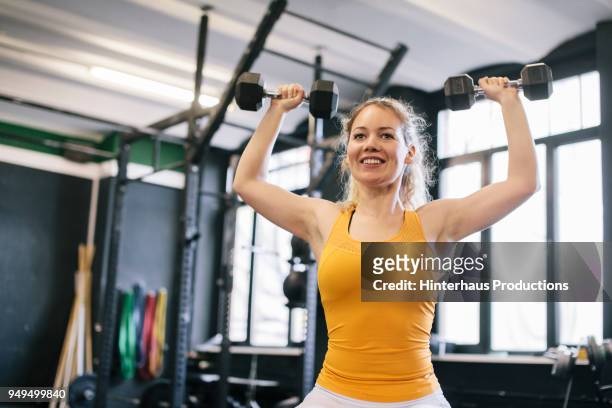 young woman doing dumbbell exercises - weightlifting imagens e fotografias de stock