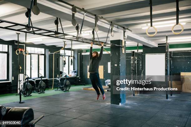 man using monkey bars at gym - monkey shoes stockfoto's en -beelden