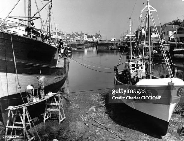 Pêcheurs repeignant la coque de leur bateau dans le port de Port-en-Bessin-Huppain dans le Calvados, en France.