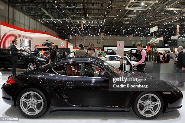 Visitor tries out a Porsche Cayman automobile prior to the 79th Geneva International Motor Show in Geneva, Switzerland, on Tuesday, March 3, 2009....