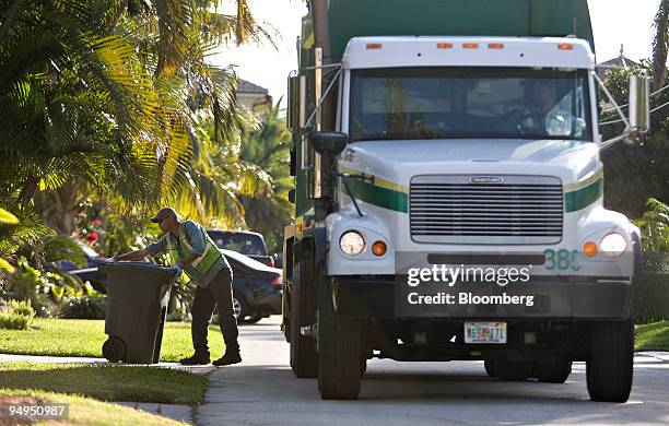 Anthony Gunari places a garbage can back on the curb after emptying it into a Waste Management truck as it collects residential trash in Lighthouse...