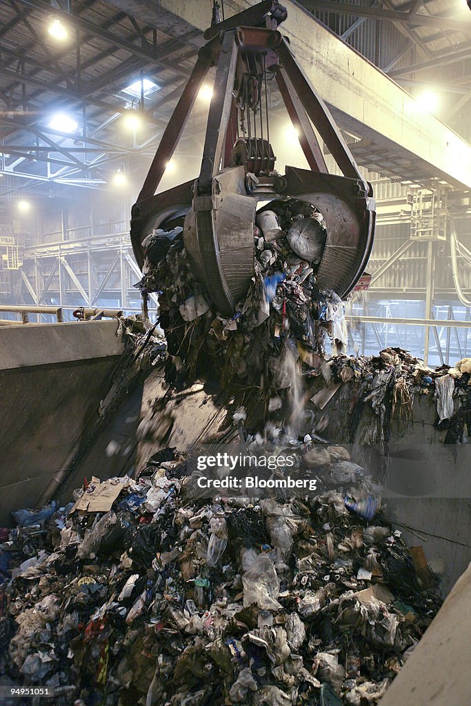 A large crane brings a load of trash from a concrete receivi