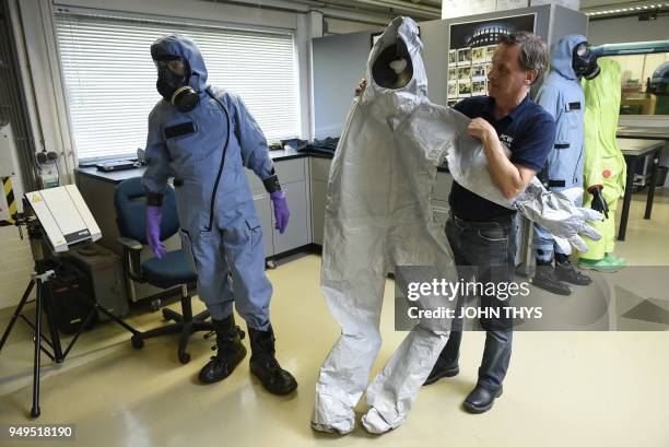 Man shows a suit used by OPCW experts in the case of Russian double agent Sergei Skripal's poisoning in Britain, as a man wears an air permeable...