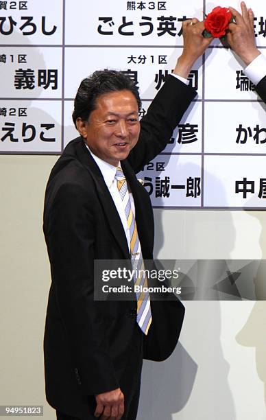 Yukio Hatoyama, president of the Democratic Party of Japan , places a red paper rose next to a DPJ candidate's name to indicate an election victory...