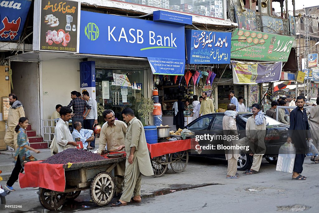 A vendor sells fruit in front of a Khadim Ali Shah Bukhari (