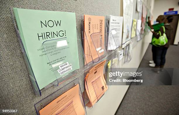 Flier reading "NOW HIRING" sits on display as Kristi Adams and Jimmy Hawkins look over other job postings nearby, inside the Riverside Workforce...