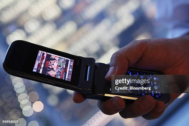 Man looks at the Soft on Demand Inc. Website on his mobile phone in Tokyo, Japan, on Tuesday, May 13, 2009. Pornography fans are feeding a surge in...