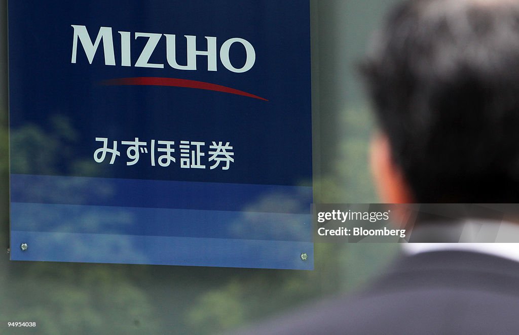 A man looks at the Mizuho Securities Co. logo, displayed out