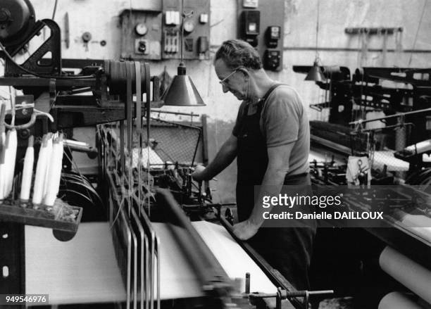 Tisserand travaillant sur un métier à tisser mécanique, à la Bâtie-Montgascon, dans l'Isère, en France.