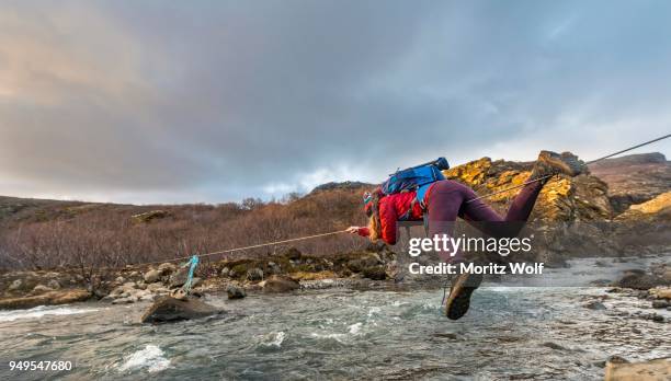 young woman crossing river with rope, botnsa river, hvalfjardarsveit, vesturland, iceland - wire rope stock pictures, royalty-free photos & images