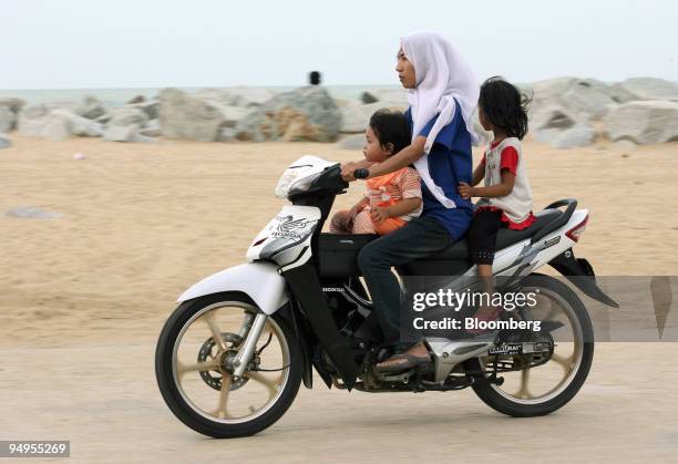 Woman and two children travel on a motorbike at Moonlight Beach, formerly called the Beach of Passionate Love, in Kota Bharu in Kelantan, Malaysia,...