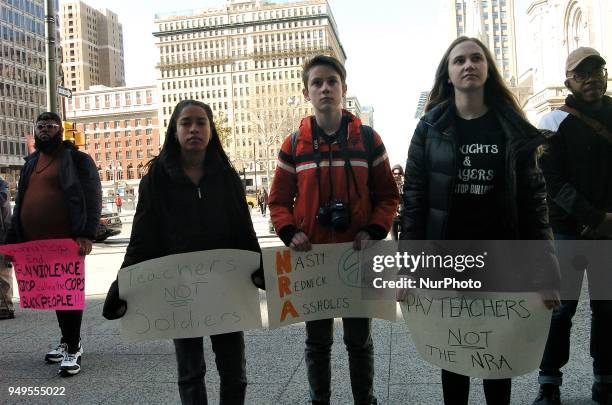 Rally attendees hold signs in support of not arming teachers during a student led walkout at city hall in Philadelphia on April 20, 2018.