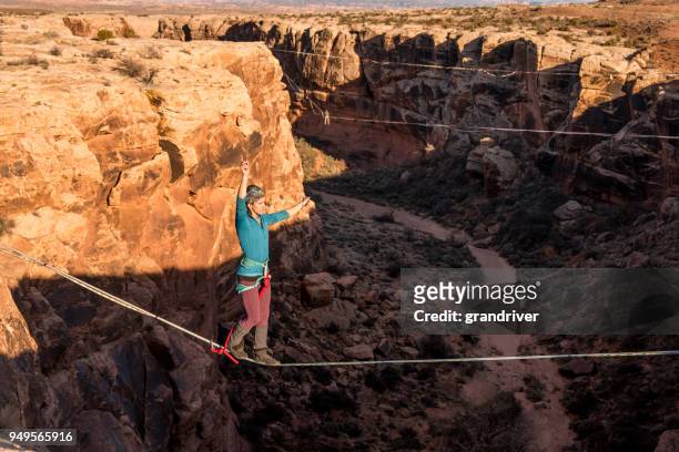 female extreme athlete highlining or slacklining near moab utah - highlining stock pictures, royalty-free photos & images
