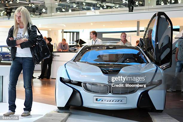 Visitor waits as a BMW Vision Efficient Dynamics automobile is loaded into its display position prior to the opening of the Frankfurt Motor Show, in...