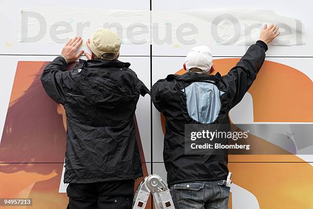 Workers hang up a sign advertising the new Opel Astra automobile prior to the opening of the Frankfurt Motor Show, in Frankfurt, Germany, on Monday,...