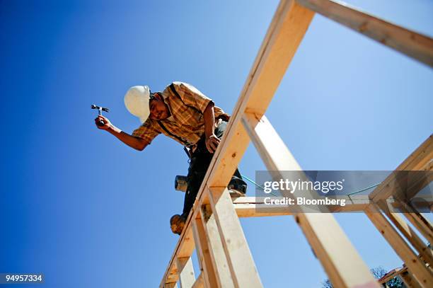 Nicolas Ramos uses a hammer to square up a board as he frames the second floor of a home under construction in Alpharetta, Georgia, U.S., on Friday,...
